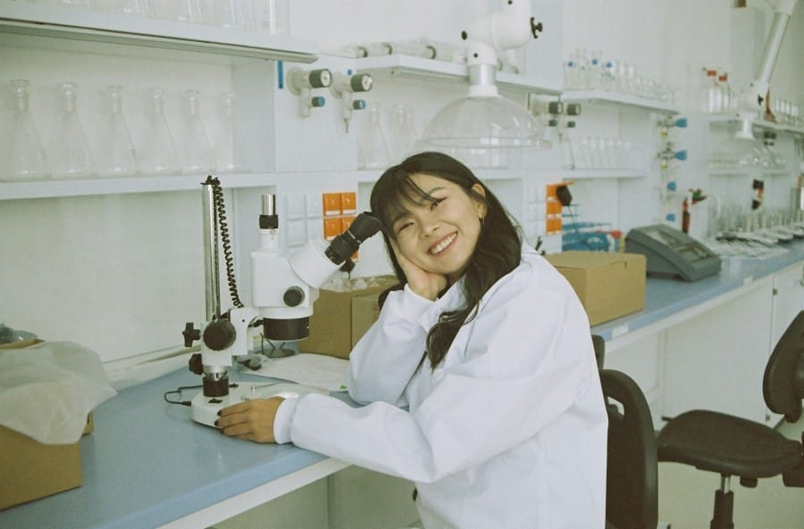 woman in white laboratory gown holding black instrument