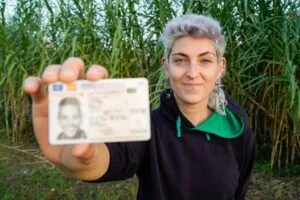 woman holding her license in a field