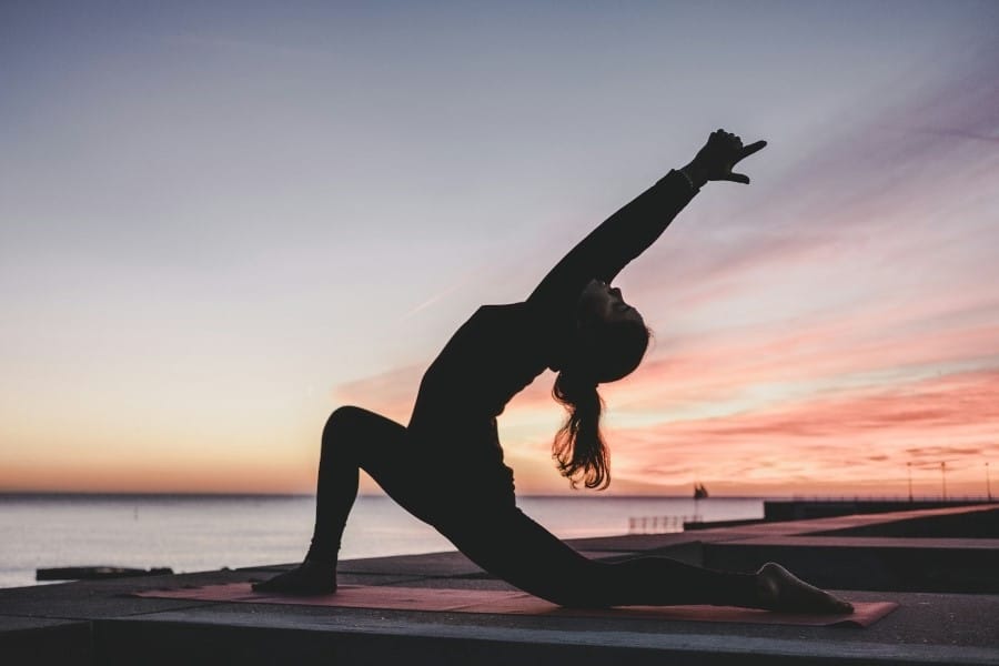 Woman doing yoga at sunset