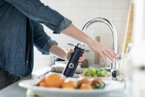 A person filling a water bottle at a sink
