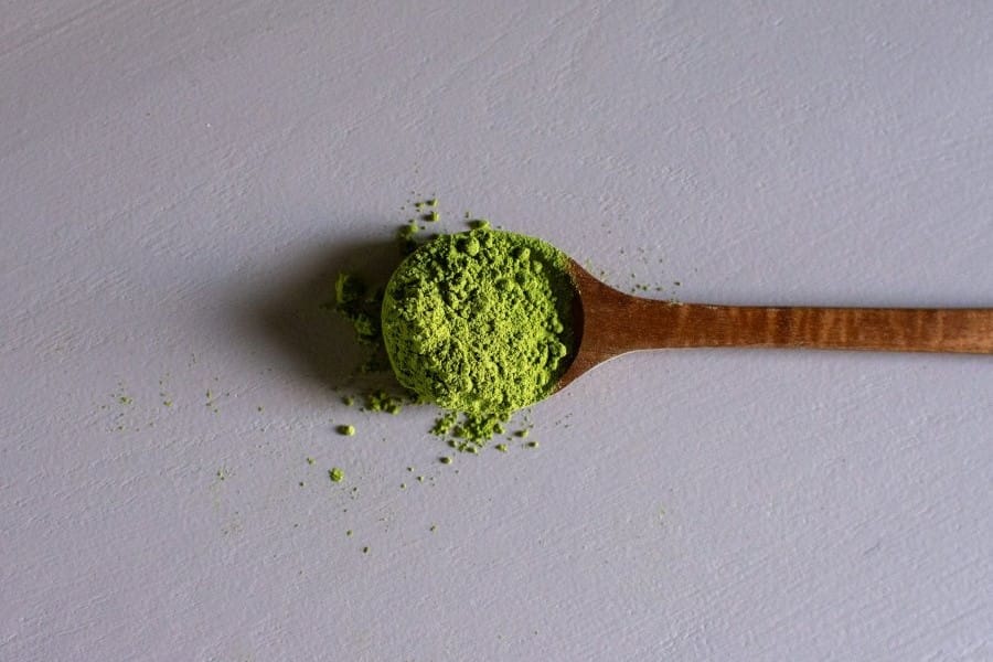 A wooden spoon full of kratom powder